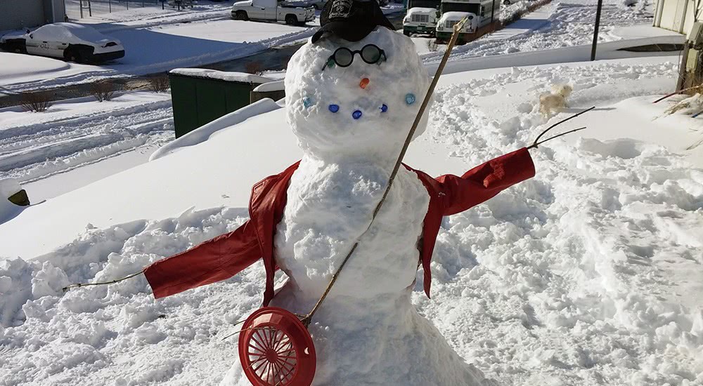 Our front-yard snowman with his whiskey hat and stick-guitar.